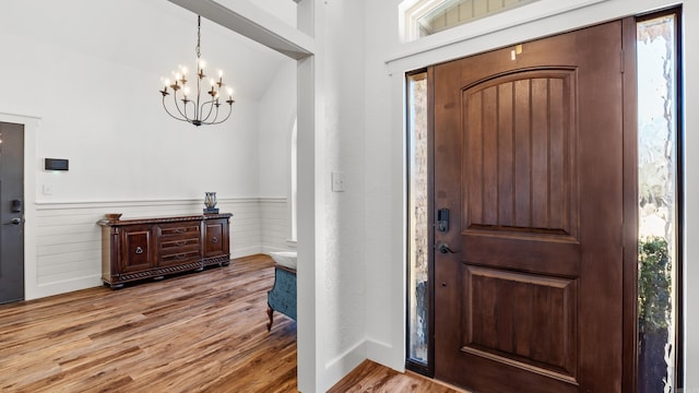 foyer entrance with wood finished floors, a wainscoted wall, and a chandelier