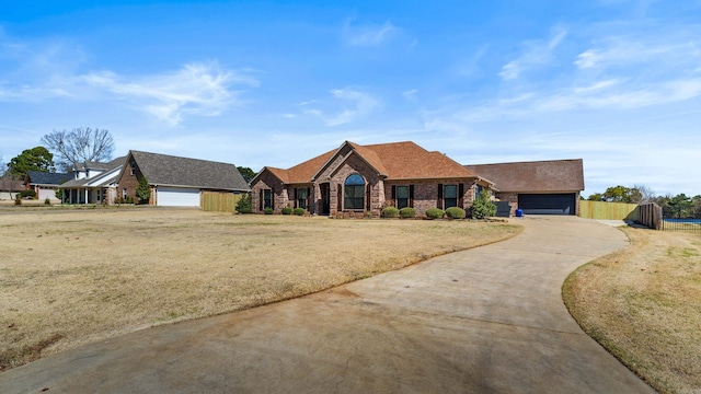 view of front of property with brick siding, fence, concrete driveway, a front yard, and an attached garage