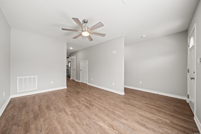 empty room with visible vents, baseboards, wood finished floors, and a ceiling fan