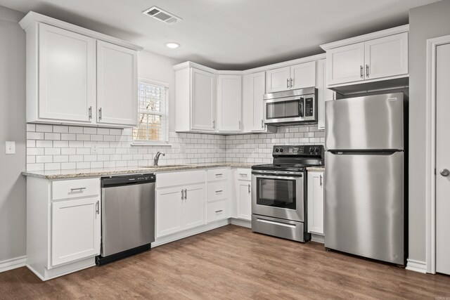 kitchen featuring appliances with stainless steel finishes, white cabinetry, and wood finished floors