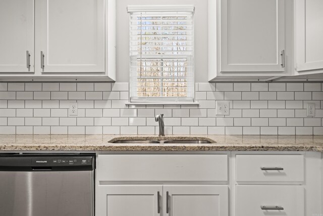 kitchen with a sink, light stone counters, tasteful backsplash, stainless steel dishwasher, and white cabinets