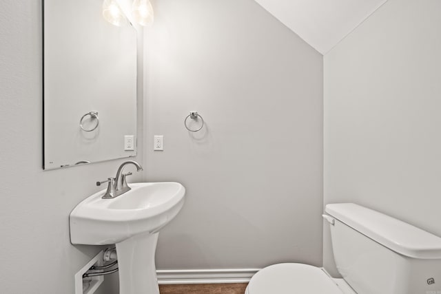 half bath with a sink, baseboards, and toilet