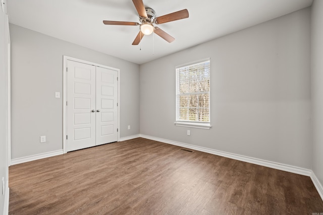 unfurnished bedroom featuring a closet, visible vents, baseboards, and wood finished floors