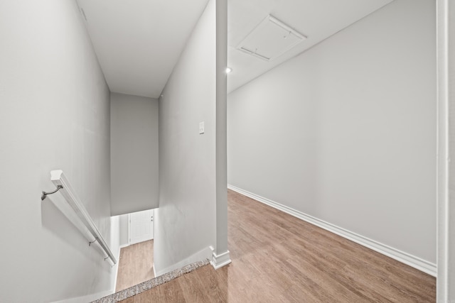 hall featuring an upstairs landing, baseboards, and wood finished floors