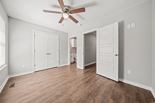 unfurnished bedroom with wood finished floors, visible vents, a closet, and baseboards