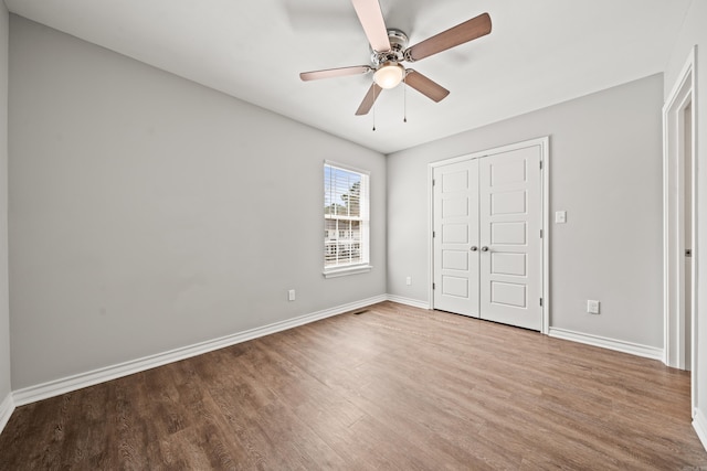 unfurnished bedroom with a closet, ceiling fan, baseboards, and wood finished floors