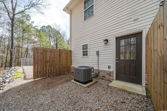 view of exterior entry featuring central AC and fence