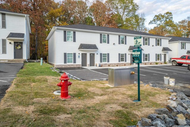 multi unit property featuring a front yard and uncovered parking