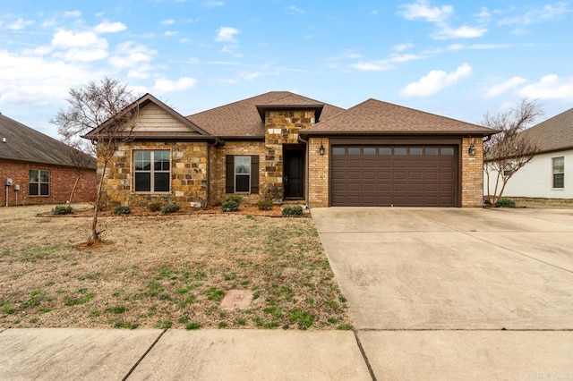 view of front of property with stone siding, a garage, driveway, and a shingled roof