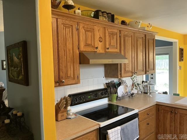 kitchen with light countertops, electric range, tasteful backsplash, and under cabinet range hood