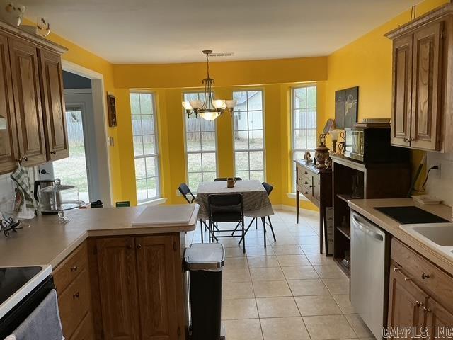 kitchen with a chandelier, light countertops, light tile patterned floors, appliances with stainless steel finishes, and a peninsula