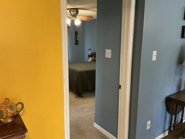 hallway with baseboards, carpet floors, and a textured ceiling