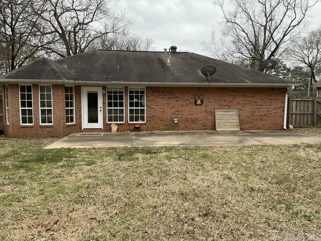 back of property featuring brick siding, a yard, a patio, and fence