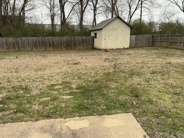 view of yard with a storage unit, an outbuilding, and a fenced backyard