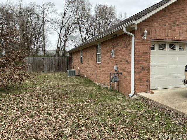 view of side of property with brick siding, central air condition unit, an attached garage, and fence