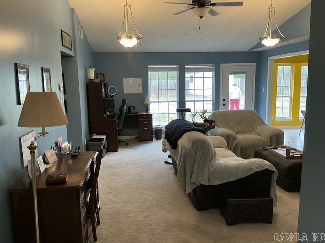 living area with plenty of natural light, light colored carpet, a ceiling fan, and vaulted ceiling