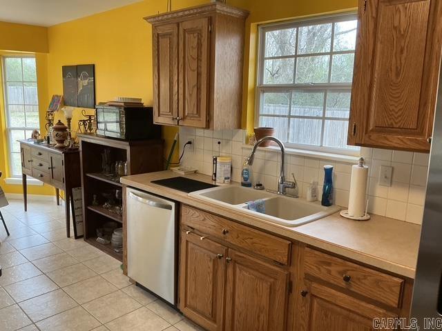 kitchen featuring a sink, plenty of natural light, light countertops, and stainless steel dishwasher