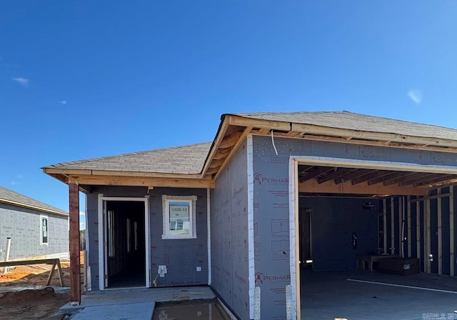 view of front facade with roof with shingles and a garage