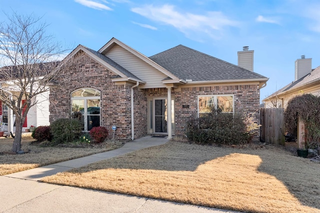 ranch-style house featuring brick siding, a chimney, and a shingled roof