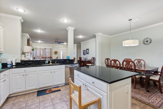 kitchen featuring a sink, decorative columns, dark countertops, and dishwasher