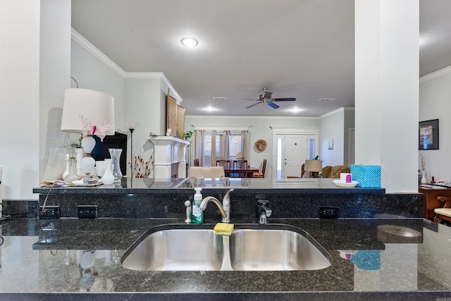 kitchen featuring visible vents, dark stone counters, ornamental molding, a ceiling fan, and a sink