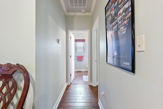 hall with visible vents, baseboards, crown molding, and dark wood-type flooring