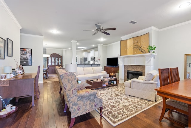 living room featuring dark wood-type flooring, crown molding, a fireplace, and visible vents