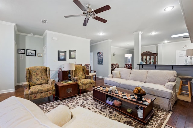 living area featuring wood finished floors, visible vents, ornate columns, baseboards, and crown molding