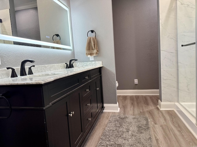 bathroom featuring walk in shower, wood finished floors, baseboards, and a sink