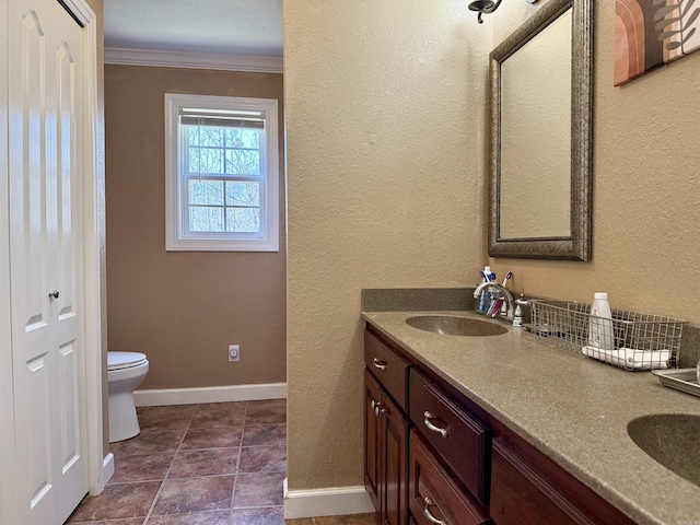 full bathroom with toilet, ornamental molding, a sink, double vanity, and baseboards