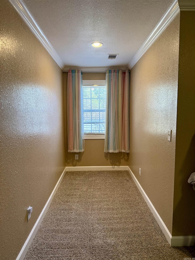 empty room with crown molding, baseboards, carpet floors, a textured wall, and a textured ceiling