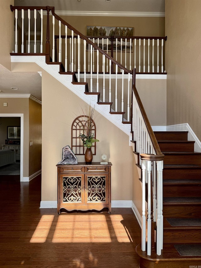 stairs with wood finished floors, baseboards, and ornamental molding