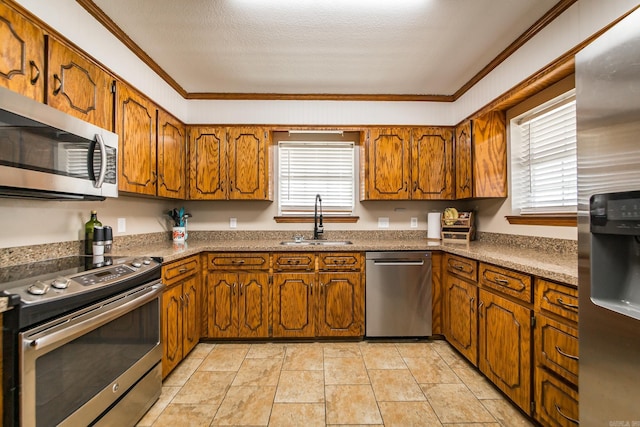 kitchen featuring light tile patterned floors, brown cabinetry, a sink, stainless steel appliances, and crown molding