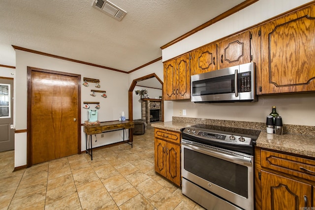 kitchen with dark countertops, ornamental molding, visible vents, and stainless steel appliances