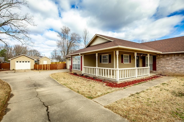 view of front facade featuring a porch, fence, an outdoor structure, concrete driveway, and a garage