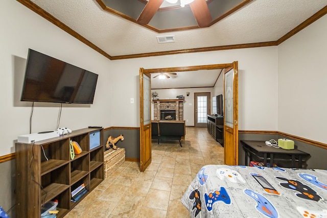 bedroom featuring crown molding, a fireplace, visible vents, and a textured ceiling