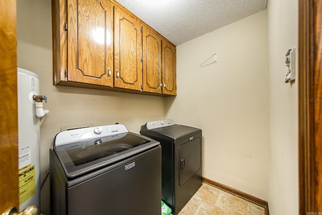 laundry area featuring washing machine and clothes dryer, baseboards, water heater, cabinet space, and a textured ceiling