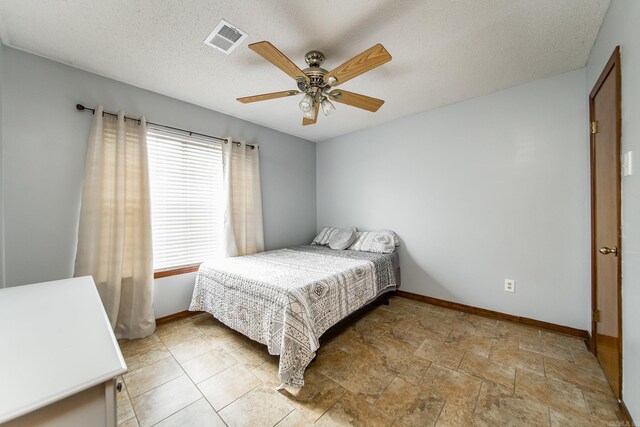 bedroom with visible vents, baseboards, a textured ceiling, and a ceiling fan