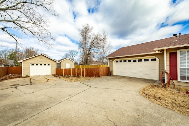 view of home's exterior with a detached garage, fence, and roof with shingles