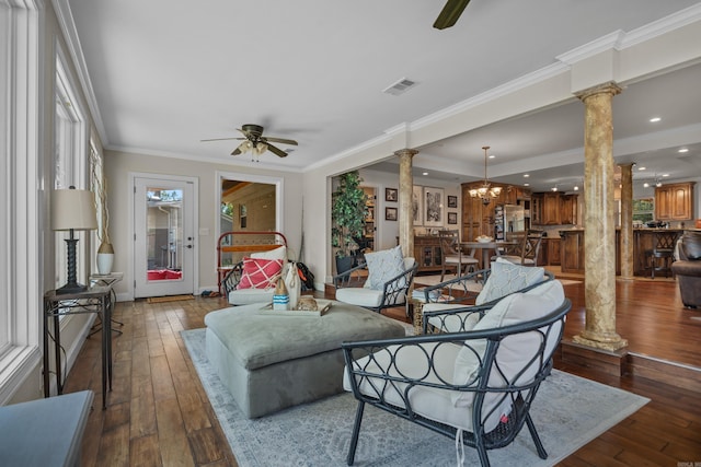 living area featuring visible vents, crown molding, hardwood / wood-style floors, ceiling fan with notable chandelier, and ornate columns