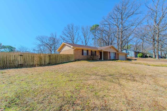 ranch-style home featuring a front lawn, brick siding, an attached garage, and fence