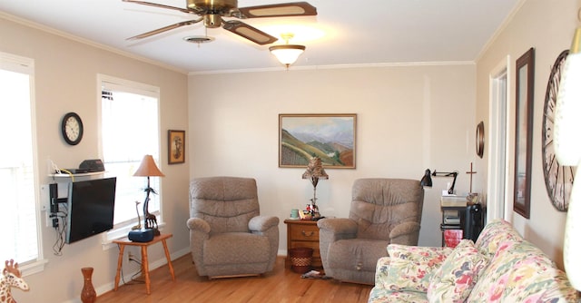 living room with a healthy amount of sunlight, wood finished floors, a ceiling fan, and ornamental molding