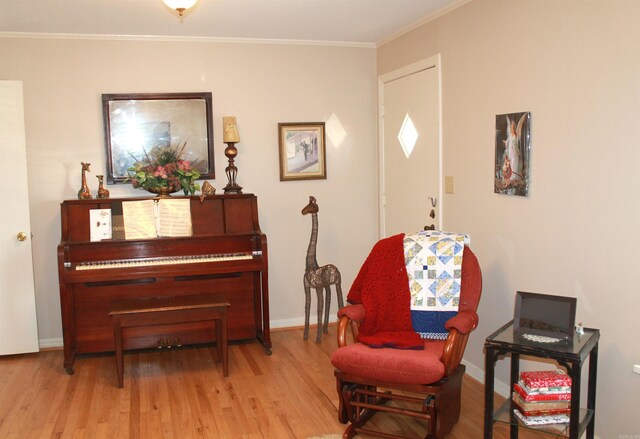 sitting room with baseboards, wood finished floors, and ornamental molding