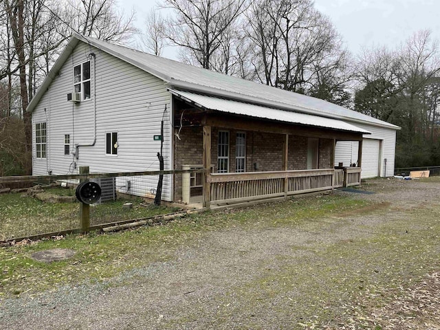 view of side of property with driveway, metal roof, an outdoor structure, a garage, and brick siding