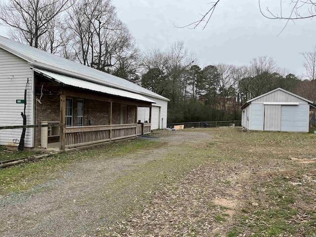 view of yard with a garage, an outbuilding, driveway, and fence