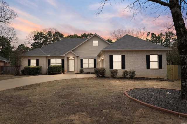 view of front of property with brick siding, roof with shingles, and fence