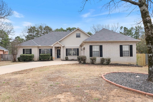 view of front of property with brick siding, a shingled roof, and fence