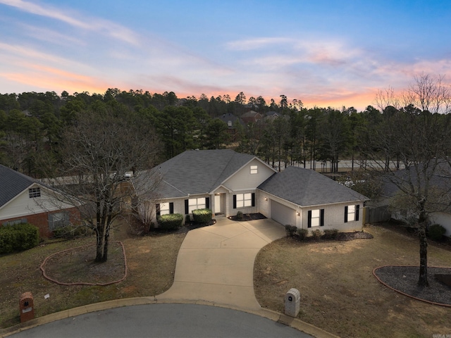 view of front of property featuring an attached garage, brick siding, driveway, and roof with shingles