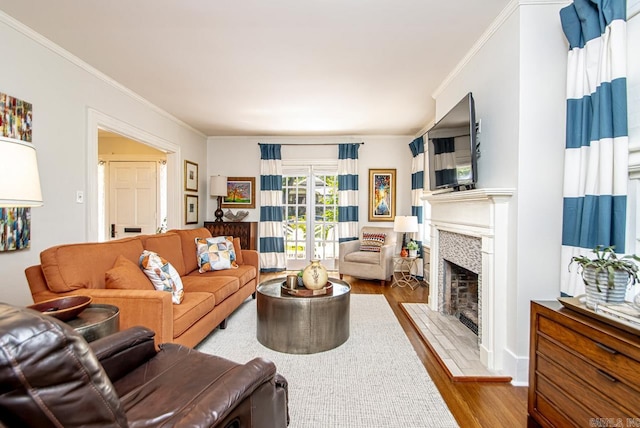 living room with a fireplace with flush hearth, wood finished floors, and crown molding