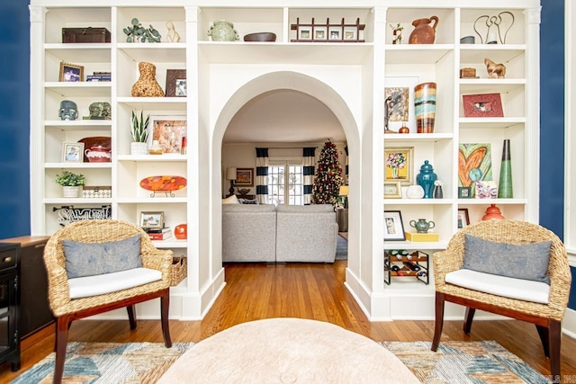 sitting room with arched walkways and wood finished floors